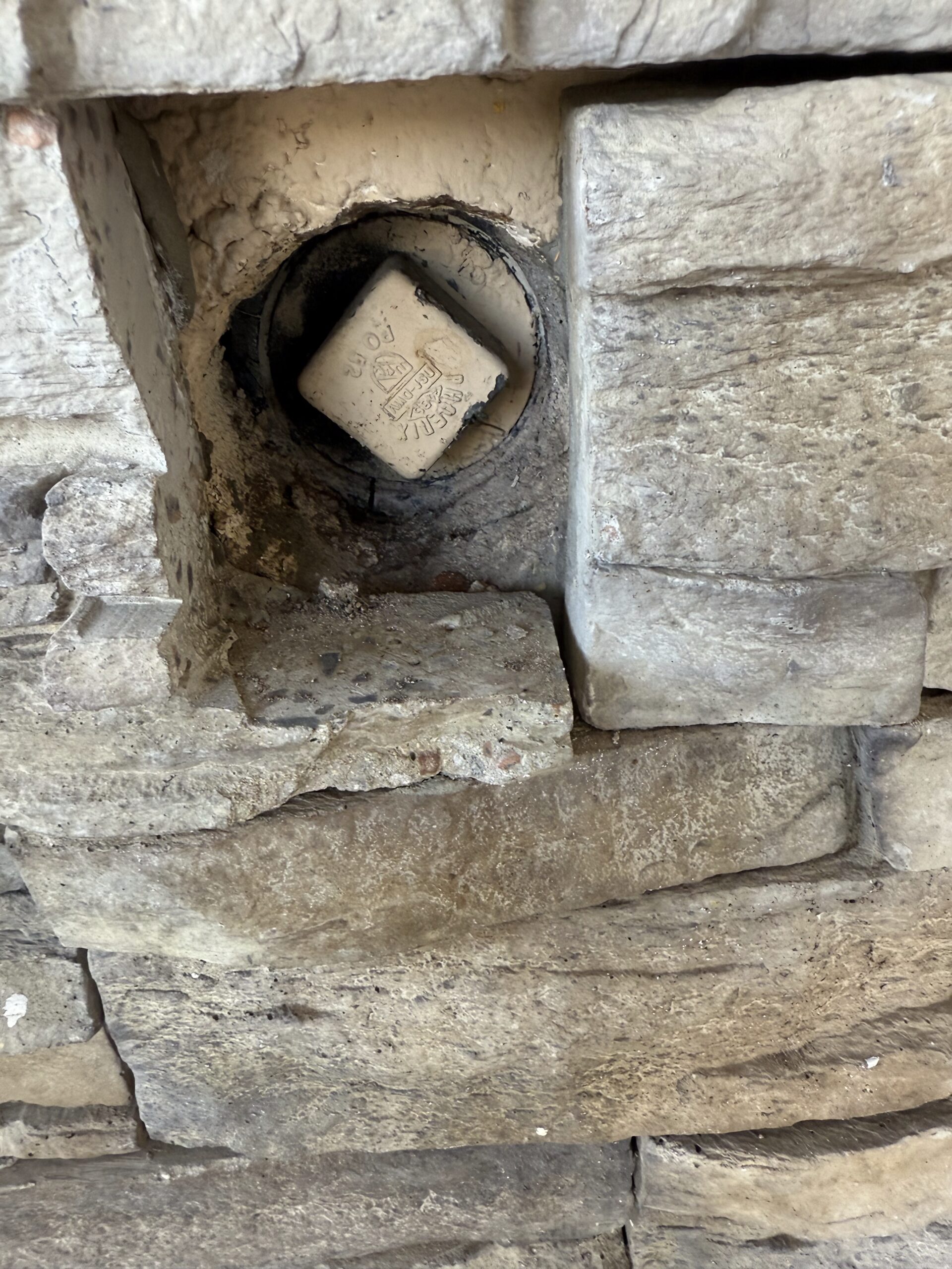 Recessed cleanout access point in stone wall, relevant for plumbing services in Phoenix, AZ, highlighting Edge Plumbing's expertise in drain clearing and maintenance.