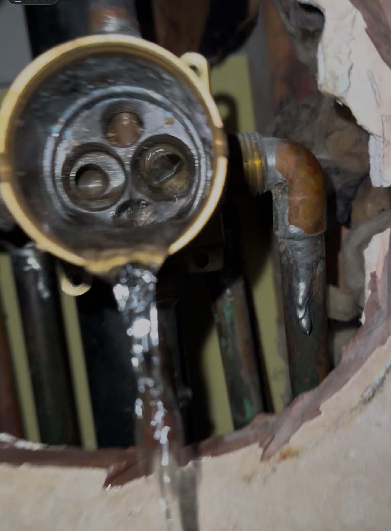 Leaking plumbing valve with water streaming from damaged pipes, illustrating urgent plumbing repair needs in Mesa, AZ.