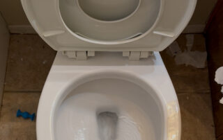 Close-up view of a white toilet bowl with water inside, featuring a clean design, relevant to plumbing tips and toilet replacement services.