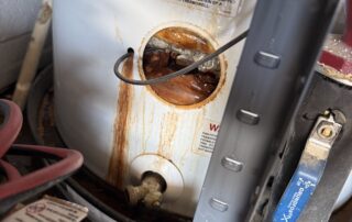 Corroded water heater with visible rust and water leakage, illustrating plumbing maintenance issues relevant to homeowners.