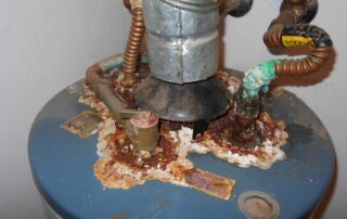 Corroded water heater with rust and mineral buildup at the base, highlighting the need for replacement or repair in plumbing maintenance.