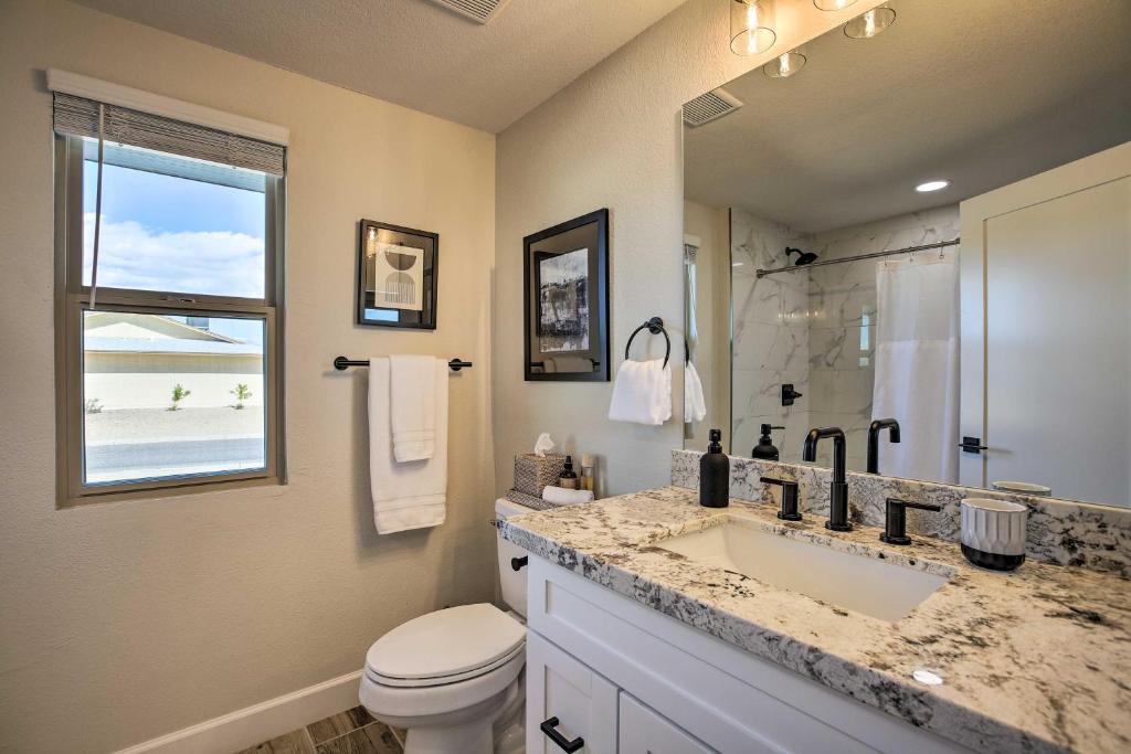 Modern bathroom interior with a white vanity, granite countertop, black faucets, framed artwork, and large window providing natural light.
