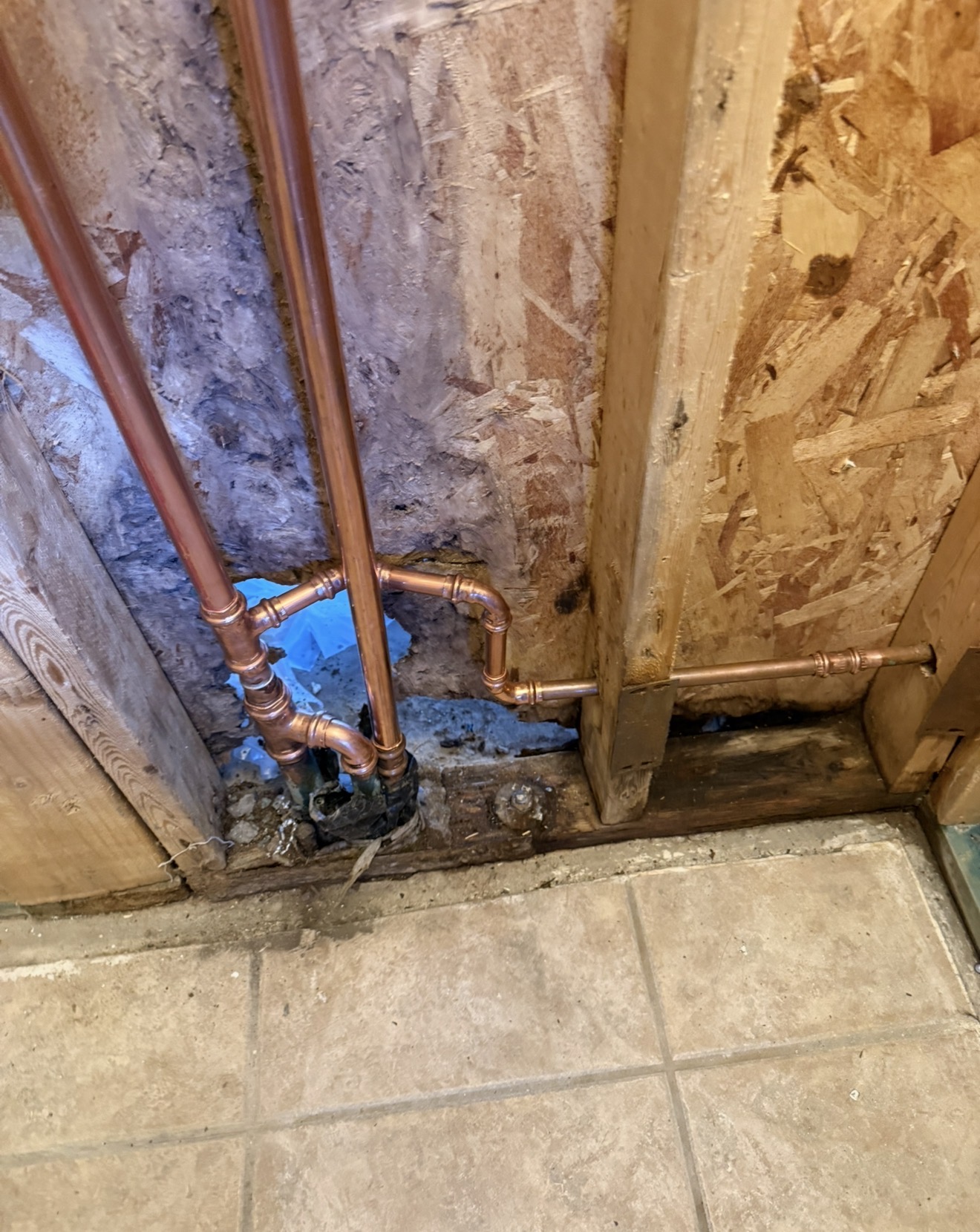 Copper plumbing pipes installed in wall, showcasing sewer repair work in residential setting, emphasizing plumbing services offered by Edge Plumbing LLC in West Valleys, AZ.