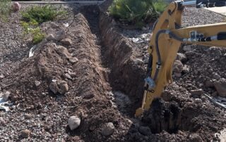 Excavation site with a trench and heavy machinery for water line replacement in Surprise, AZ.