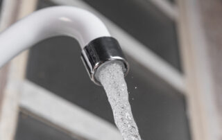 Close-up of a white kitchen sink faucet with running water, illustrating plumbing features relevant to home maintenance in Surprise, AZ.